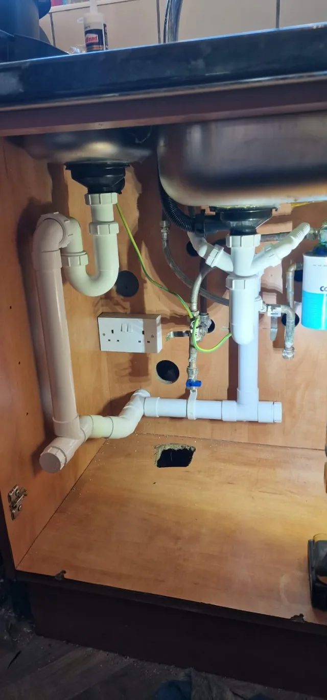 Completed replacement waste connections beneath the kitchen sink in Rayne