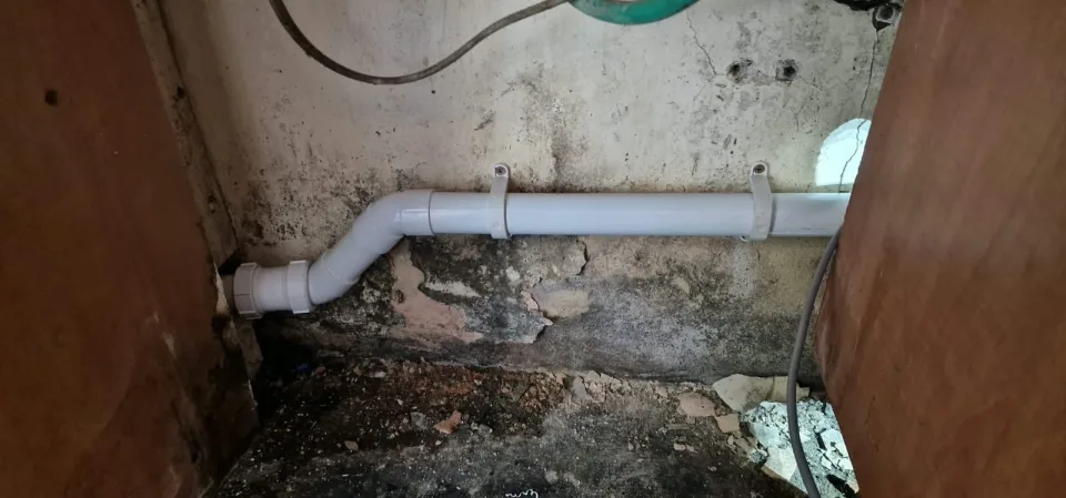 Replacement white waste pipe secured to the wall at the Rayne kitchen job